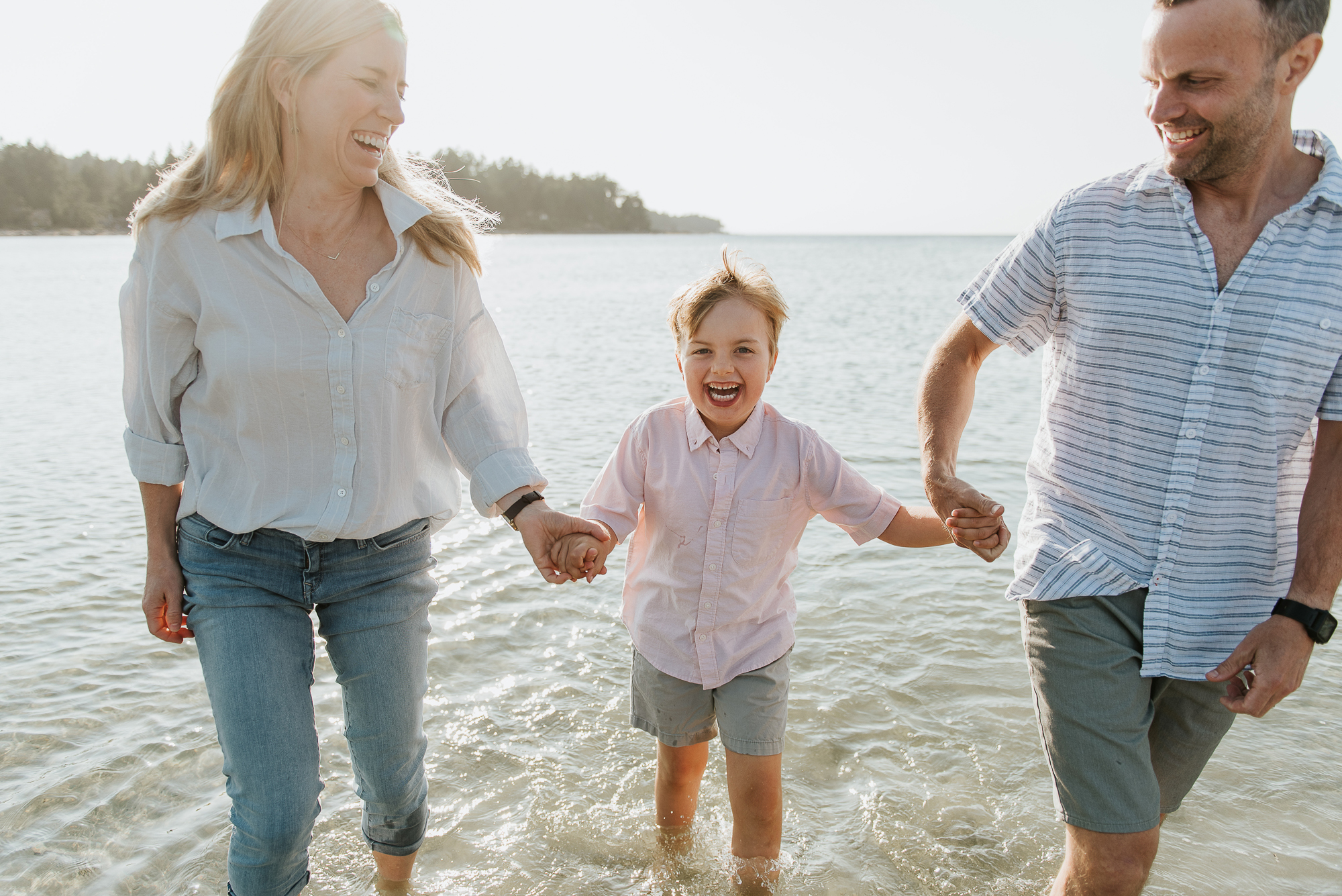 Claire and Matt with Jake holding hands at the beach. Jake has a big smile.
